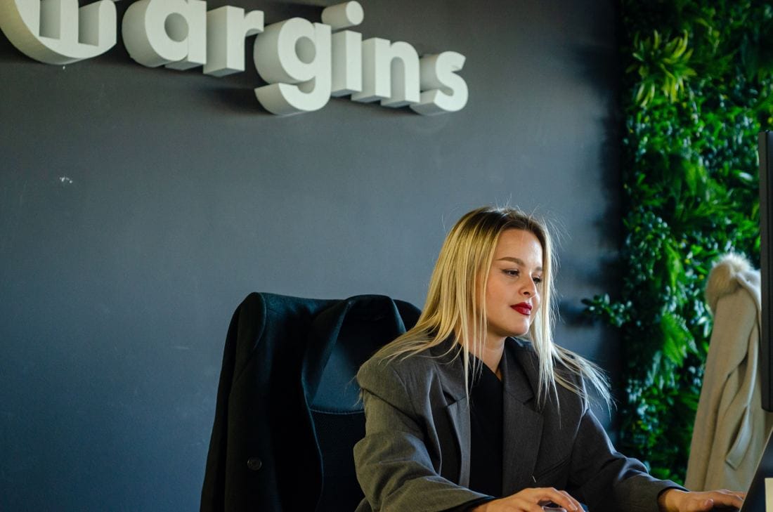 A Margins team member at work beneath the Margins logo wall
